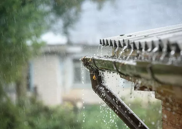 Rainwater flowing from house roof gutter